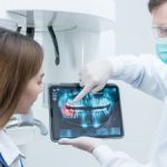 A dentist with a digital dental imaging showing the dental issue to the woman patient.