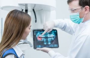 A dentist with a digital dental imaging showing the dental issue to the woman patient.