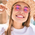 smiling girl in pink glasses and hat