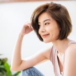 Portrait of beautiful young asian woman with attractive smile hand touching hair in her apartment. Teenage asia girl relax in spring time, asia beauty facial skincare concept