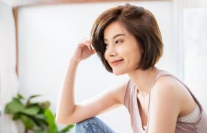 Portrait of beautiful young asian woman with attractive smile hand touching hair in her apartment. Teenage asia girl relax in spring time, asia beauty facial skincare concept